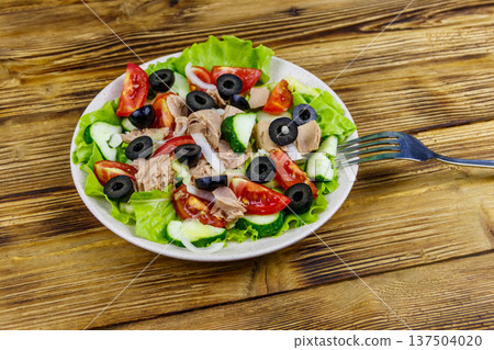Tasty tuna salad with lettuce, black olives and fresh vegetables on wooden table Tasty tuna salad with lettuce, black olives and fresh vegetables on wooden table 137504020