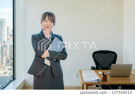 A female office worker pondering in the office 137504419