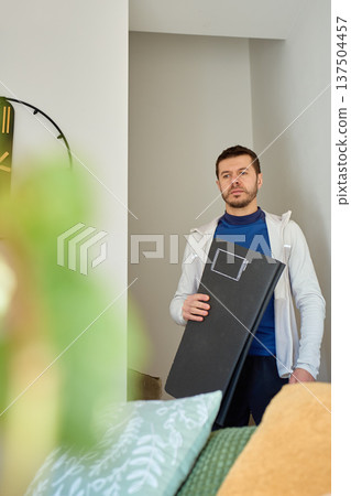 Man carrying exercise mat in living room before home workout 137504457