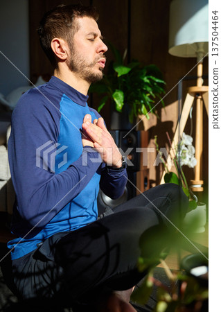 Man sitting on mat with hands on chest during home breathing practice Man sitting on mat with hands on chest during home breathing practice 137504464