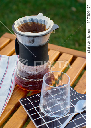 Pour over coffee brewing in glass carafe with dripper outdoors 137504471