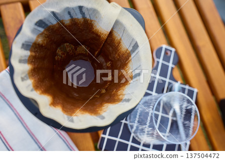 Used coffee filter with grounds residue in dripper on glass carafe Used coffee filter with grounds residue in dripper on glass carafe 137504472