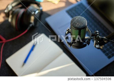 Podcast microphone above desk with headphones laptop and notebook 137504506