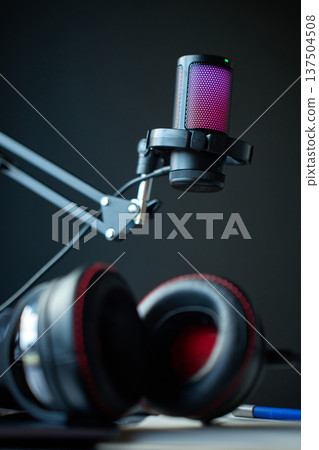 Podcast microphone on boom arm above desk with headphones 137504508