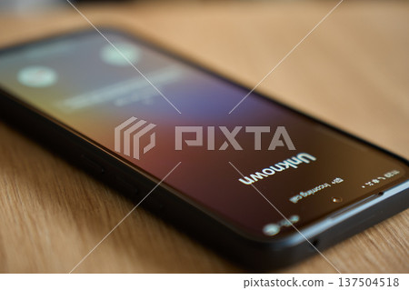 Smartphone screen with unknown incoming call on wooden table close up 137504518
