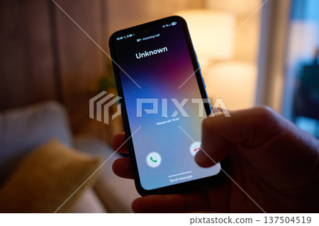 Hand holding smartphone showing unknown incoming call on screen Hand holding smartphone showing unknown incoming call on screen 137504519