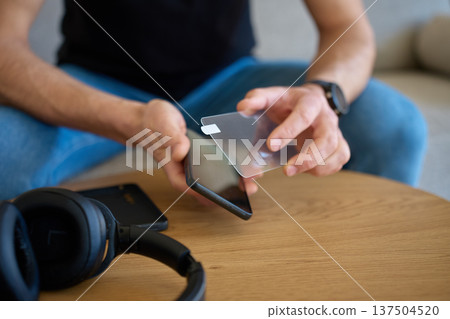 Man applying protective glass screen protector to smartphone at home Man applying protective glass screen protector to smartphone at home 137504520