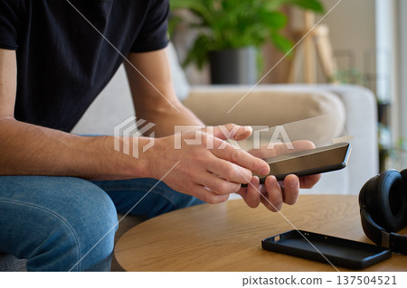 Man applying protective glass screen protector to smartphone at home Man applying protective glass screen protector to smartphone at home 137504521