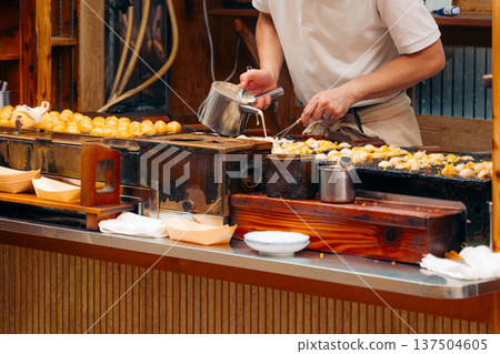 Osaka chef prepares takoyaki, a popular Japanese street food snack Osaka chef prepares takoyaki, a popular Japanese street food snack 137504605