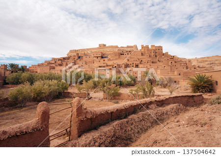 Moroccan kasbah Ait Ben Haddou with palm trees and tourists exploring 137504642