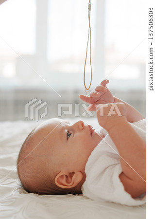 Baby gazing at a necklace dangling above Baby gazing at a necklace dangling above 137506303