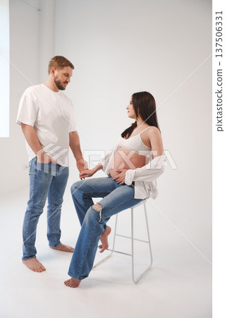 Expecting couple sharing a tender moment in a studio 137506331