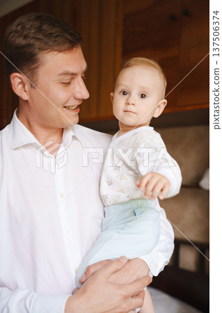 Father holds baby in cozy indoor setting Father holds baby in cozy indoor setting 137506374