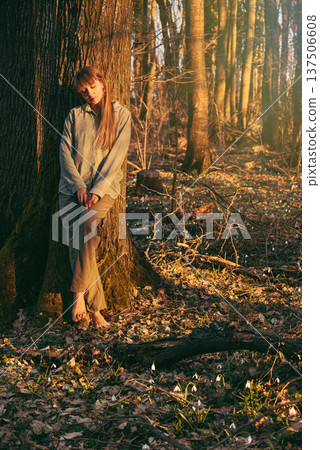 Woman Leaning Against Tree in Early Spring Forest 137506608