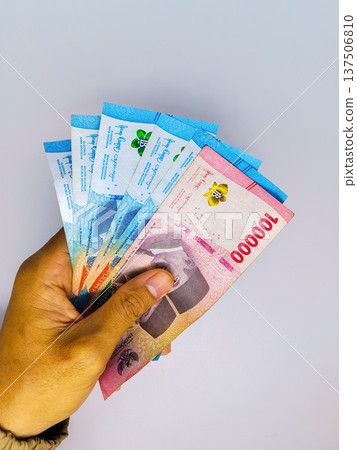 Hand holding banknote of indonesian rupiah on white background. financial transactions Hand holding banknote of indonesian rupiah on white background. financial transactions 137506810