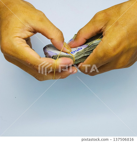 Hands tie money with rubber bands, closeup of photo indonesian rupiah Hands tie money with rubber bands, closeup of photo indonesian rupiah 137506816
