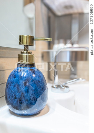 Blue ceramic soap dispenser on white sink 137506999