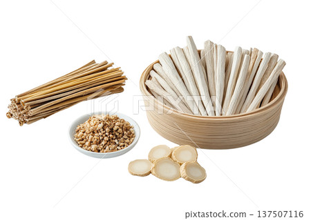 An assortment of dried Thai herbs and spices  including fragrant galangal slices  arranged in a wooden bowl alongside wooden sticks on a clean white background  This image showcases the natural 137507116