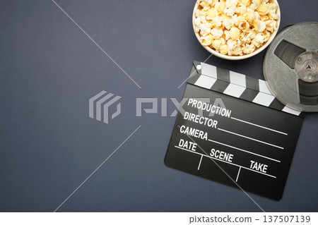 Movie clapper with popcorn and film reels on dark blue background Movie clapper with popcorn and film reels on dark blue background 137507139