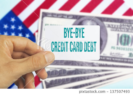 Human hand holding a plastic credit card with text bye bye credit card debt against a background of US dollar bills. Conceptual photography symbolizing financial freedom, paying off personal loans Human hand holding a plastic credit card with text bye bye credit card debt against a background of US dollar bills. Conceptual photography symbolizing financial freedom, paying off personal loans 137507493