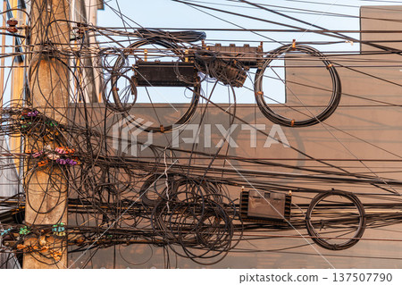 Mess of electrical and internet cables on utility pole in Thailand urban infrastructure 137507790