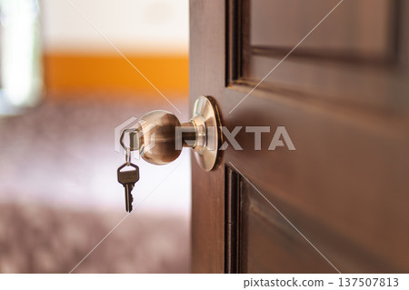 House door with metal doorknob and key inserted in lock inside residential interior House door with metal doorknob and key inserted in lock inside residential interior 137507813