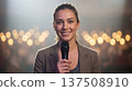 Smiling reporter holds microphone on stage. Microphone interview for election coverage, press conference, live broadcast concept, bokeh lights, news story, microphone closeup, media branding 137508910