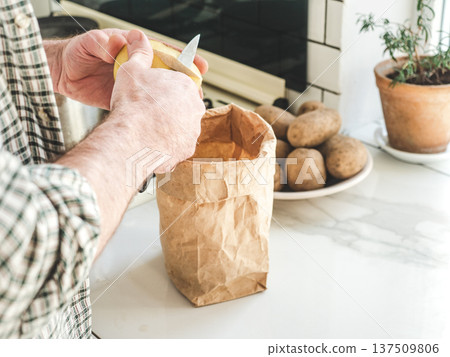 Man's hands peel a potato 137509806