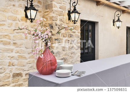 Long outdoor buffet table against stone wall with pink blossoms at a wedding 137509831