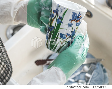 Man in green rubber gloves washes dishes Man in green rubber gloves washes dishes 137509959