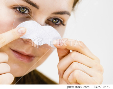 Woman applying pore strips on nose Woman applying pore strips on nose 137510469