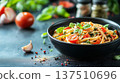 Delicious pasta dish with fresh tomatoes and basil, elegantly presented in a black bowl, surrounded by garlic, spices, and vibrant green herbs, showcasing culinary artistry and flavor 137510696
