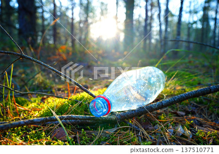 Plastic bottle thrown away in forest. Garbage in nature, reusable products. Rubbish thrown in forest Plastic bottle thrown away in forest. Garbage in nature, reusable products. Rubbish thrown in forest 137510771