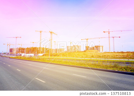 Empty road during sunlight near construction site with cranes in city area. Renovation, building Empty road during sunlight near construction site with cranes in city area. Renovation, building 137510813