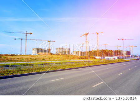 Empty road during sunlight near construction site with cranes in city area. Renovation, building Empty road during sunlight near construction site with cranes in city area. Renovation, building 137510814