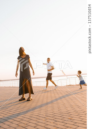 Pregnant Mother Enjoying Sunset While Family Plays Nearby Pregnant Mother Enjoying Sunset While Family Plays Nearby 137510854