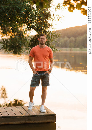 Casual Man Standing By The Lake Sunset Casual Man Standing By The Lake Sunset 137511034