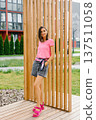 Beautiful Young Woman in Pink t Shirt Posing near Wooden Partition Outdoors 137511058