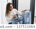 Woman Comparing Denim Jeans in Mall Shop 137511064