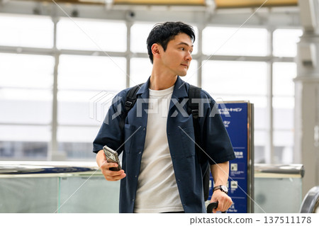 A man holding a smartphone at a station. Photo courtesy of Kansai International Airport (KIX). 137511178