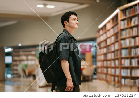 一名男子在書店裡尋找一本書。 一名男子在書店裡尋找一本書。 137511227