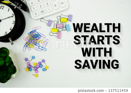 Wealth Starts With Saving message with calculator, alarm clock and Stationery on white background Wealth Starts With Saving message with calculator, alarm clock and Stationery on white background 137511459