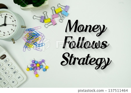 Money Follows Strategy message with calculator, alarm clock and Stationery on white background 137511464