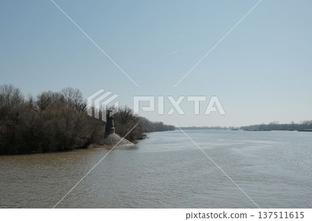 Historic river lighthouse standing at the riverbank near Pancevo on the Danube river in Serbia. Calm water landscape with navigation tower used as a landmark for river transport and shipping 137511615