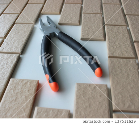 Rubberized Handles Of Pliers On Free Space On A Surface Covered With Brick Tiles. Home Repairing Square Stock Photo Rubberized Handles Of Pliers On Free Space On A Surface Covered With Brick Tiles. Home Repairing Square Stock Photo 137511629