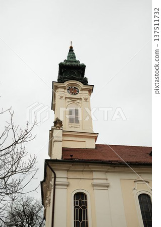 Yellow church tower with clock and decorative facade in Sombor, Serbia. Christian landmark and European heritage architecture concept 137511732