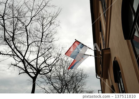 Serbian flags on historic building facade in Sombor, Serbia under cloudy sky. National identity, European city architecture and travel concept Serbian flags on historic building facade in Sombor, Serbia under cloudy sky. National identity, European city architecture and travel concept 137511810