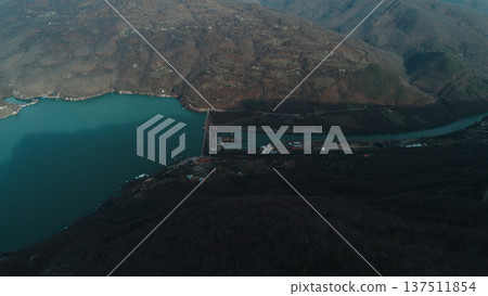 Aerial view of the Perucac Lake dam on the Drina River with mountainous landscape and Bosnia visible on the opposite riverbank. Winter scenery without snow in western Serbia Aerial view of the Perucac Lake dam on the Drina River with mountainous landscape and Bosnia visible on the opposite riverbank. Winter scenery without snow in western Serbia 137511854