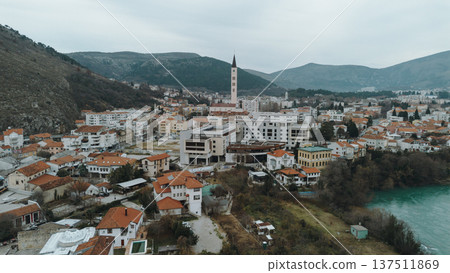 Aerial view of Mostar city with residential neighborhoods, modern buildings, and the turquoise Neretva River framed by surrounding hills in Bosnia and Herzegovina Aerial view of Mostar city with residential neighborhoods, modern buildings, and the turquoise Neretva River framed by surrounding hills in Bosnia and Herzegovina 137511869