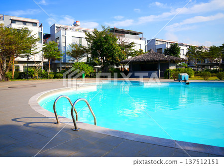 Swimming pool with turquoise water surrounded by dreamy beach hotel buildings, trees in lounge area  137512151
